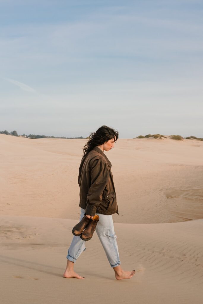 a woman walking across a sandy beach